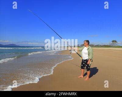 Une femme d'âge moyen pêchant sur la plage à Grassy Head, Nouvelle-Galles du Sud, Australie Banque D'Images