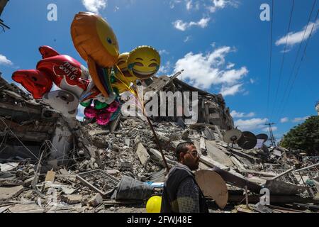 Gaza, Palestine. 22 mai 2021. Un homme palestinien vend des ballons près des décombres de la tour Al Shorouq.les Gazaouis ont essayé de redorer leur vie après un conflit dévastateur de 11 jours avec Israël qui a tué plus de 200 personnes et fait des milliers de sans-abri dans l'enclave palestinienne appauvrie. Crédit : SOPA Images Limited/Alamy Live News Banque D'Images