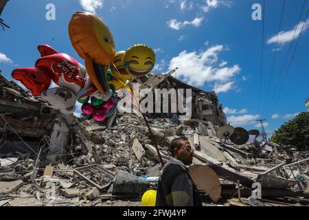 Gaza, Palestine. 22 mai 2021. Un homme palestinien vend des ballons près des décombres de la tour Al Shorouq.les Gazaouis ont essayé de redorer leur vie après un conflit dévastateur de 11 jours avec Israël qui a tué plus de 200 personnes et fait des milliers de sans-abri dans l'enclave palestinienne appauvrie. (Photo par Ahmed Zakot/SOPA Images/Sipa USA) crédit: SIPA USA/Alay Live News Banque D'Images