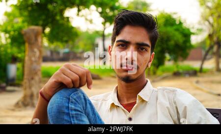Portrait d'un jeune homme en bonne santé assis à l'extérieur dans le parc et regardant l'appareil photo.
