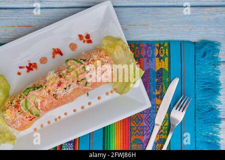 Péruvien traditionnel plat appelé causa faite de purée de piment (AJI) et le jus de lime et remplie de légumes (maïs, pois, carottes) et Banque D'Images