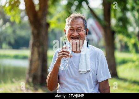 Happy asian actif senior asiatique homme de boire de l'eau après l'exercice dans le parc, concept de senior sain mode de vie. Banque D'Images