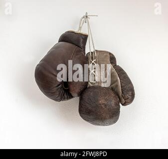 Vieux gants de boxe suspendus sur un mur blanc Banque D'Images