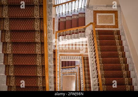 Vue vers le bas de l'escalier en colimaçon avec plusieurs vols décorés de tapis. Banque D'Images