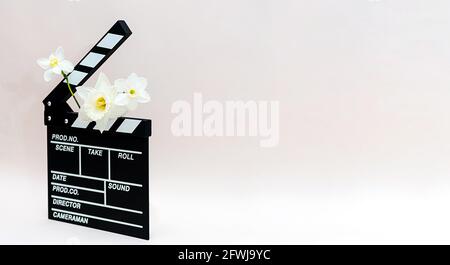 Tableau de bord d'un film avec fleurs printanières. Durée de vie minimale de la planche clapper pour faire du cinéma vidéo et des fleurs de jonquilles. Banque D'Images