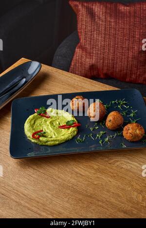 plat de guacamole et de falafel sur une plaque bleue sur une table en bois. Photo pour le menu. Concept de la nourriture, du petit déjeuner, du matin et du déjeuner. Banque D'Images