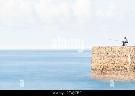 Homme pêche au bout de la jetée Banque D'Images