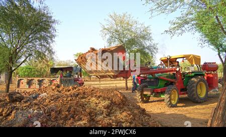 07 mai 2021 - Reengus, Sikar, Inde. Jeune Indien utilisant un tracteur lourd avec loder . Le fermier remplit l'engrais organique dans un chariot de chargement t Banque D'Images