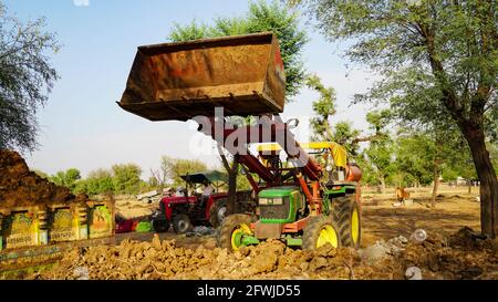 07 mai 2021 - Reengus, Sikar, Inde. Jeune Indien utilisant un tracteur lourd avec loder . Le fermier remplit l'engrais organique dans un chariot de chargement t Banque D'Images