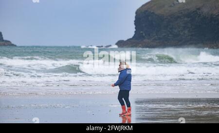 Polzeath, Cornwall, Royaume-Uni. 23 mai 2021. Météo Royaume-Uni. Ce matin, marcheur sur la plage à Polzeath a enveloppé à nouveau la pluie et le vent. Crédit Simon Maycock / Alamy Live News. Banque D'Images