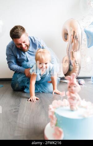 Le père et le dauther célèbrent l'anniversaire de leur petite fille. Fête d'anniversaire en robes et ballons bleus. Banque D'Images