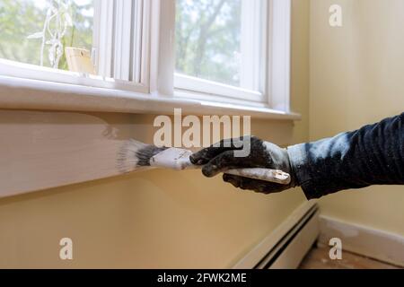 Le handyman peint un cadre de moulure de fenêtre à la maison Banque D'Images