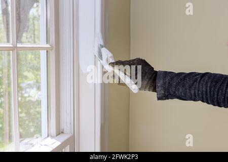 Rénovation à la maison dans les peintures de handyman avec un pinceau un cadre de moulure de vitre Banque D'Images