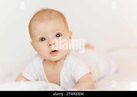 Portrait d'adorable petite fille sur un lit confortable à la maison, beau tout-petit mignon regarder l'appareil photo avec grand intérêt, l'enfance et la garde d'enfants Banque D'Images