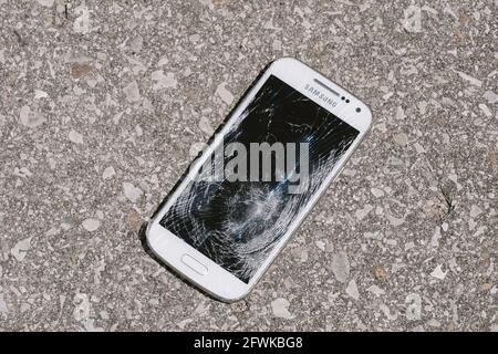 téléphone avec écran cassé sur sol en béton Banque D'Images
