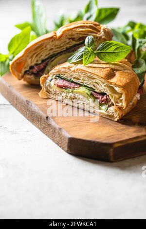 Croissant sandwich au concombre, avocat, tomate, épinards, pastrami de boeuf, sauce sur bois. Mise au point sélective Banque D'Images