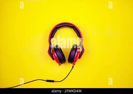 Vue de dessus du casque rouge sur fond de papier jaune clair Flat Lay minimal Top Down Flat Lay sans fil Headphones objet prise de vue en studio. Banque D'Images