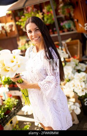 Jolie jeune femme achetant des fleurs au marché aux fleurs Banque D'Images