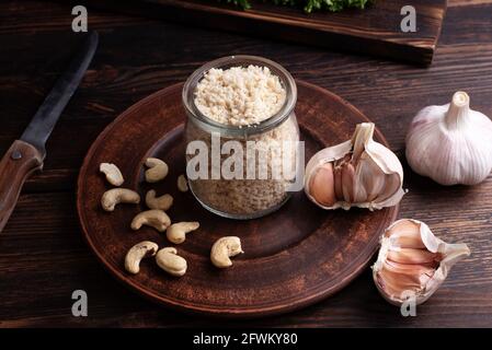 Fromage parmesan végétarien sain à base de noix de cajou moulées dans un pot sur fond de bois, style rustique, gros plan. Banque D'Images