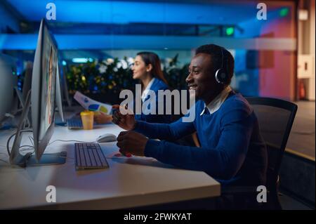 Deux managers souriants travaillent dans le bureau de nuit Banque D'Images
