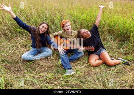 Vacances d'été musique de vacances Happy People concept. Groupe de trois amis garçon et deux filles avec chant de guitare chant chant s'amuser ensemble en plein air Banque D'Images