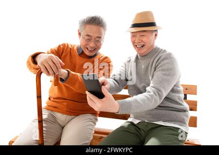 Les deux vieux amis se sont assis sur le banc pour regarder un téléphone portable Banque D'Images