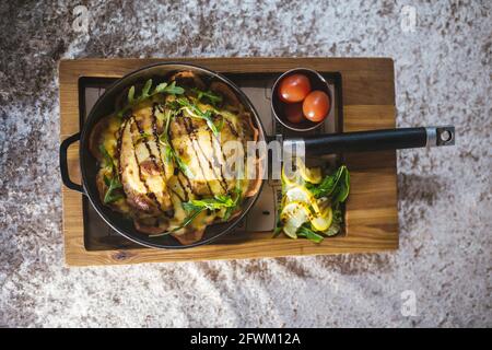 frites dans une poêle avec tomates sur un support en bois. Banque D'Images