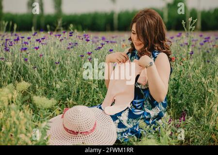 Gros plan sur une jeune maman qui profite de sa maternité et qui la tient vêtements pour bébés à venir Banque D'Images