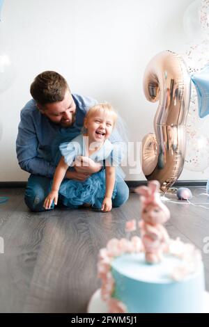 Le père et le dauther célèbrent l'anniversaire de leur petite fille. Fête d'anniversaire en robes et ballons bleus. Banque D'Images