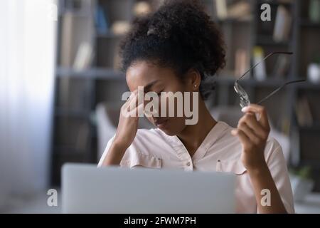 Femme africaine millénaire épuisée souffrant du syndrome des yeux secs. Banque D'Images