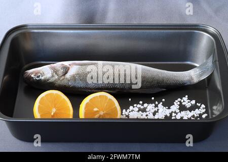 Poisson de mer frais cru bar de mer avec citron et gros sel sur un plateau Banque D'Images