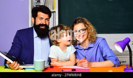 Rôle parental. Les parents aident son fils à faire ses devoirs pour l'école. Étudiant élémentaire. Mentorat, enseignement, concept d'éducation. Banque D'Images