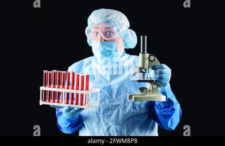 Médecin avec des tubes à sang et un microscope. Un technicien de laboratoire analysant un échantillon de sang en clinique. Banque D'Images