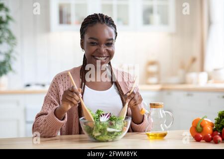 Bonne femme afro-américaine souriante préparant de la salade de légumes frais Cuisine Banque D'Images