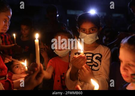 Gaza. 23 mai 2021. Des enfants palestiniens allument des bougies dans les décombres de la maison d'une famille dont les enfants ont tous été tués lors d'un raid israélien dans le camp de réfugiés de Shati, à l'ouest de la ville de Gaza. Crédit : CIC de la majorité mondiale/Alamy Live News Banque D'Images