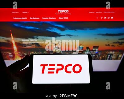 Personne détenant un smartphone avec le logo de Tokyo Electric Power Company Holdings Inc. (TEPCO) à l'écran devant le site Web. Mise au point sur l'affichage du téléphone. Banque D'Images