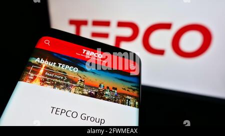 Téléphone mobile avec page Web de Tokyo Electric Power Company Holdings Inc. (TEPCO) à l'écran devant le logo. Faites la mise au point dans le coin supérieur gauche de l'écran du téléphone. Banque D'Images
