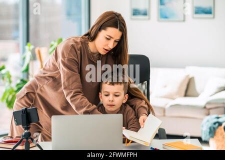 Mère aide son fils avec l'éducation à distance en ligne Banque D'Images