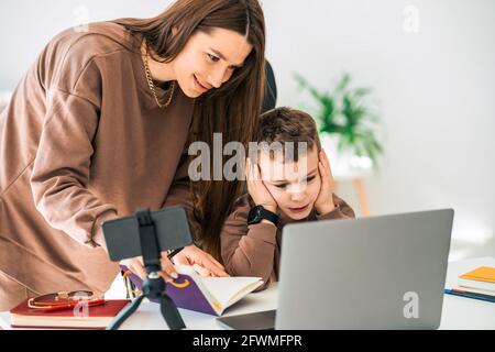 Mère aide son fils avec l'éducation à distance en ligne Banque D'Images