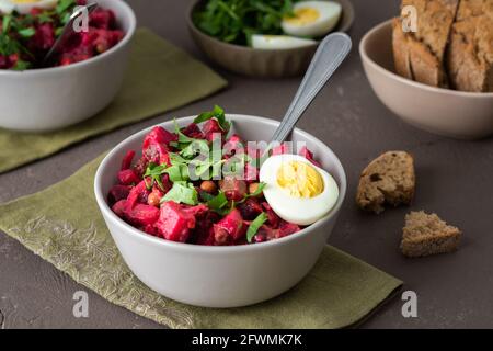 Vinaigrette russe à salade dans des assiettes avec œufs durs et pain noir, salade de légumes durs et marinés et pois verts en conserve Banque D'Images