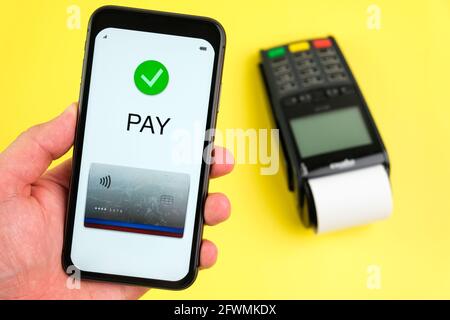 Application de paiement sans contact sur l'écran du smartphone et borne de position sur fond jaune. Banque D'Images