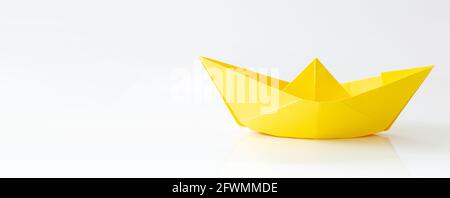 Bateau à papier jaune isolé sur fond blanc avec espace de copie, bannière Banque D'Images