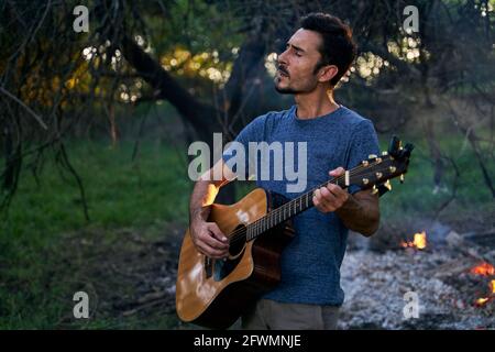 portrait du jeune musicien jouant de la guitare au coucher du soleil Banque D'Images