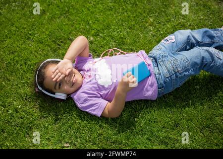 bonne fille de latina en utilisant un smartphone et un casque sur le terrain de sport Banque D'Images