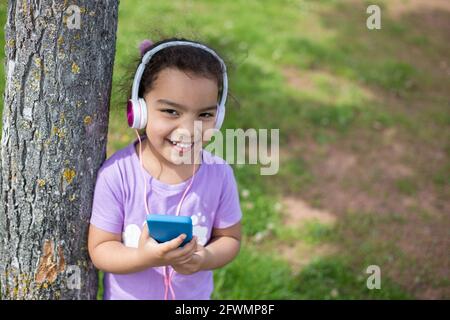 bonne fille de latina en utilisant un smartphone et un casque sur le terrain de sport Banque D'Images