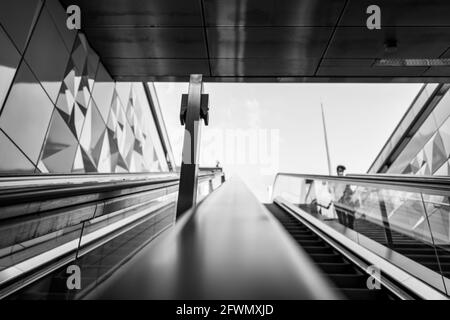 Vue défocaisée et à angle bas, tons noir et blanc, vue intérieure de l'escalier sur la main courante de l'escalier roulant depuis la station de métro sans personne Banque D'Images