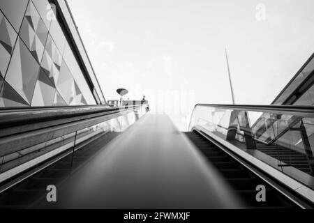 Vue défocaisée et à angle bas, tons noir et blanc, vue intérieure de l'escalier sur la main courante de l'escalier roulant depuis la station de métro sans personne Banque D'Images