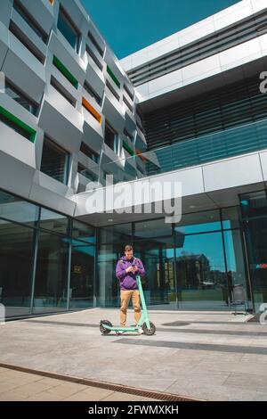 un jeune homme conduit un kick-scooter électrique à la liste des bâtiments de bureau le mode de vie urbain de transport de miles Banque D'Images
