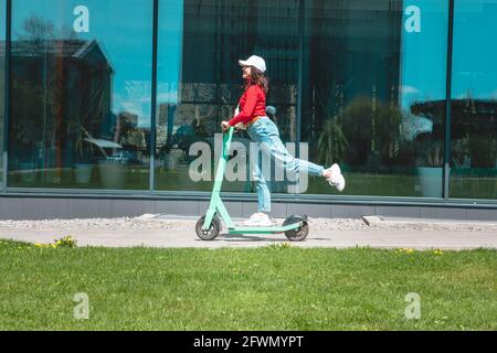 jeune femme à cheval électrique kick scooter copier l'espace printemps ensoleillé jour Banque D'Images