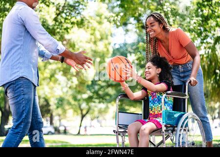 Fille en fauteuil roulant jouant au basket-ball avec sa famille. Banque D'Images